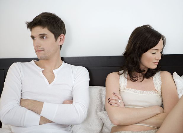 Couple sitting up in bed, arguing