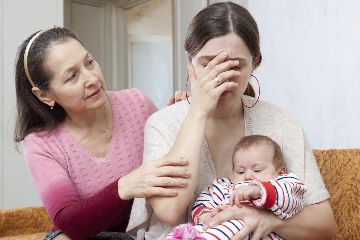 a woman being consoled by an older woman while she holds her infant child
