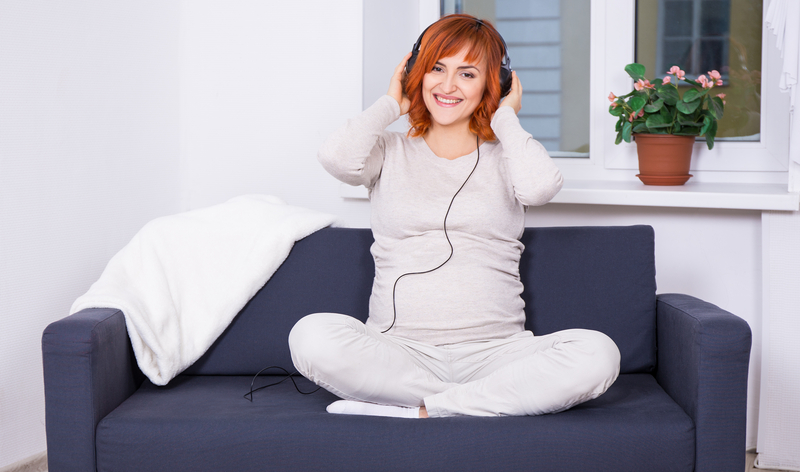 red haired woman sitting on a smile couch, wearing headphones doing music therapy