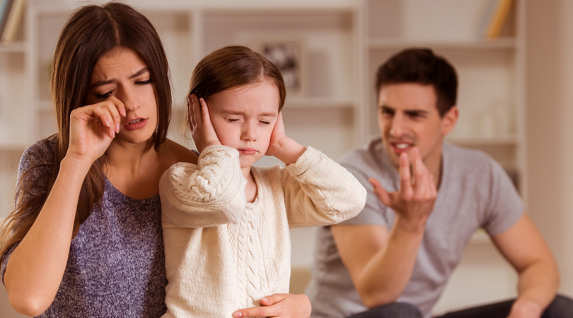 Young parents arguing while child holds her hands over her ears.